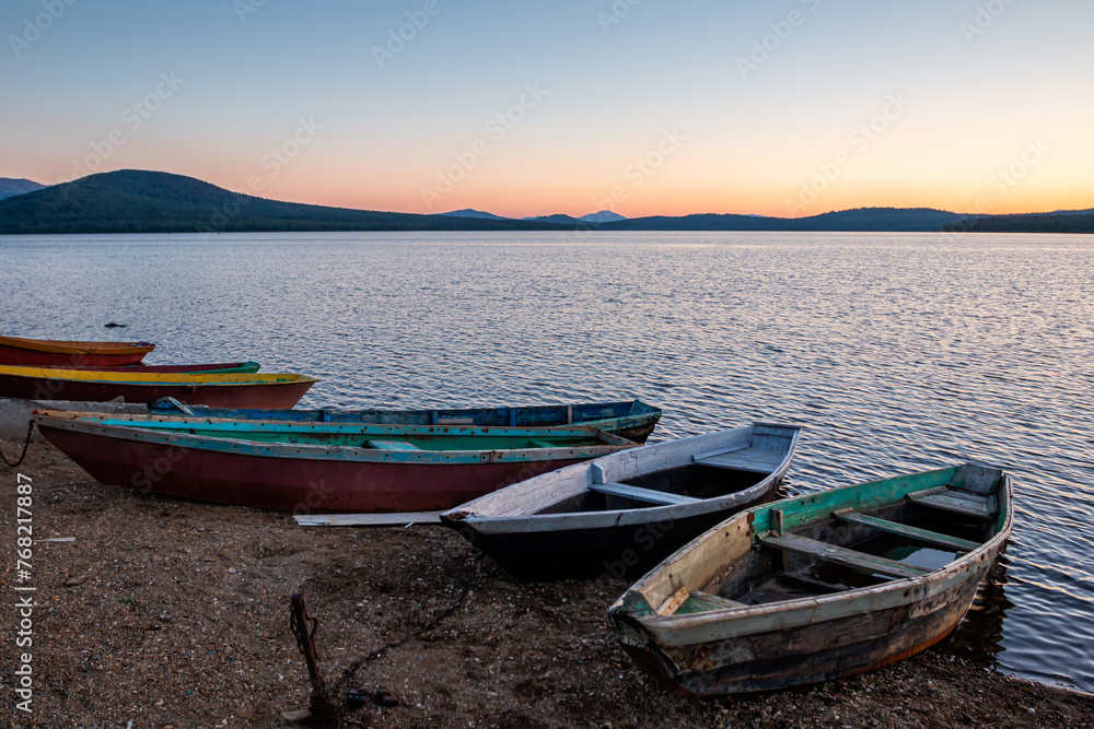 Wooden boats on the shore of a lake on a sunset summer evening