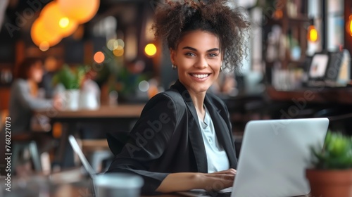 Young happy business woman company employee sitting at desk working on laptop. Smiling female professional entrepreneur worker using computer in corporate modern office looking at camera