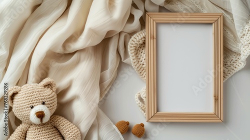 a modern minimalistic square wooden frame mockup on a light wood table, complemented by a teddy bear toy and baby blanket, all bathed in soft beige tones and warm lighting, captured from a top view.