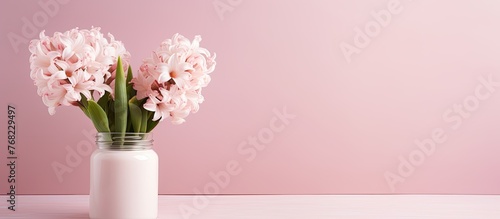 Pink flowers are arranged in a vase placed on the surface of a table