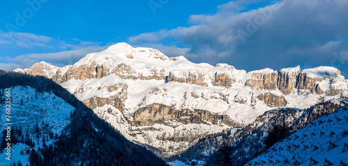 Dolomites in Italy. Sella mountain massif and mountain range at rising sun in March, covered with snow. Panoramic view from Pieve di Livinalogo near Arabba, famous ski and snowboard resort