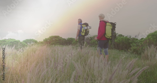 Caucasian senior couple hiking in countryside, over fast moving clouds and sunset