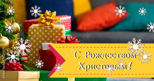 Image of christmas greetings in russian over presents and snow falling