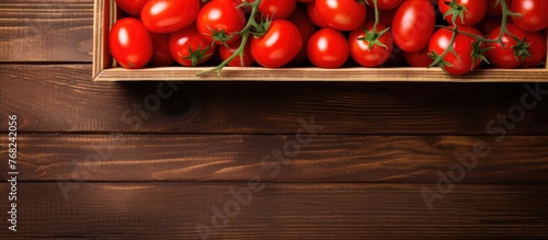 A top view of a wooden crate overflowing with vibrant red cherry tomatoes. The crate is full to the brim with the fresh produce, showcasing a bountiful harvest.