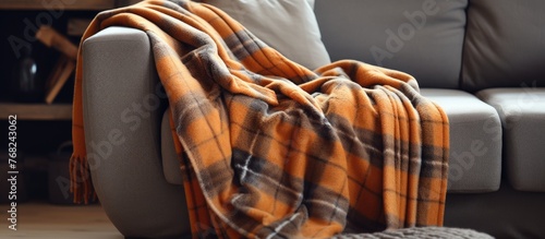A folded woolen checked blanket rests neatly on a plush couch, creating a warm and inviting atmosphere perfect for autumn and winter.
