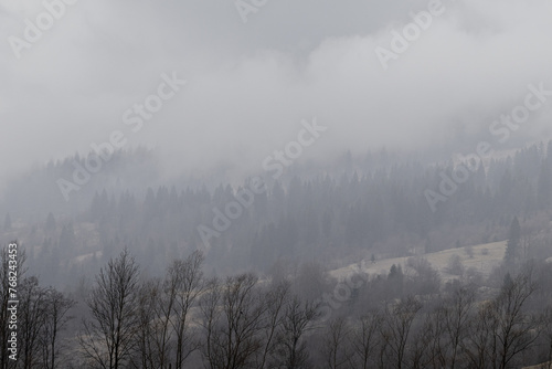 Yasinya, Ukraine. March 17, 2024, early spring, cloudy rainy sky. an incredibly beautiful view of the fog-shrouded mountains. small village houses in which people live.