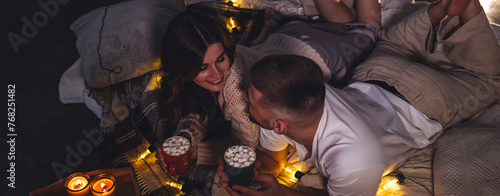 Banner. Romantic surprise for girlfriend or boyfriend for Saint Valentine's Day. Bedroom prepared for watching movies decorated with lights, candles. Cozy home Christmas atmosphere, hot chocolate