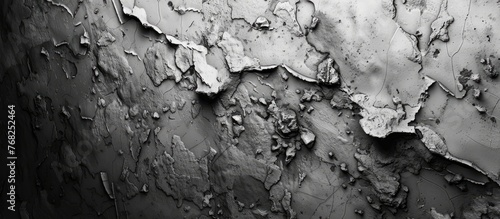 A black and white photo showing the peeling paint on a concrete wall, revealing layers of texture and history. The paint is cracked and chipped, adding character to the worn surface.