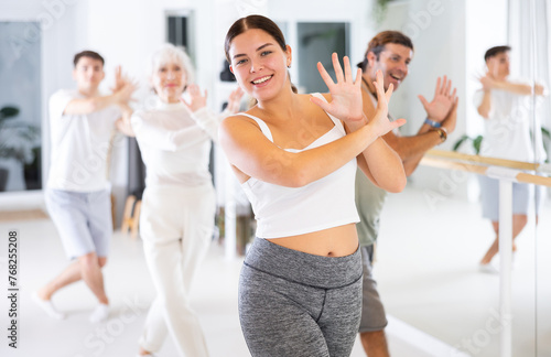 Cheerful young and adult men and women training in dance fitness studio. Aerobic class for adults.