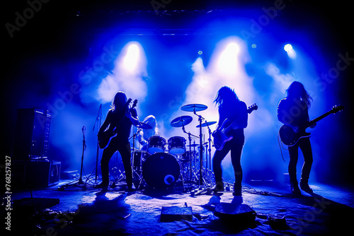 A band of four musicians playing on stage with a purple