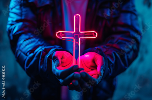 Man on street holding Christian cross made of neon lights, street in neon signs modernity of religion © Alina Zavhorodnii