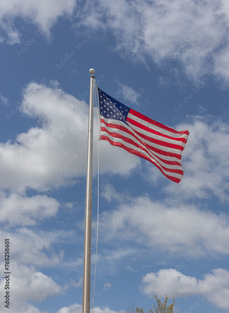 American flag waving against blue sky with white clouds