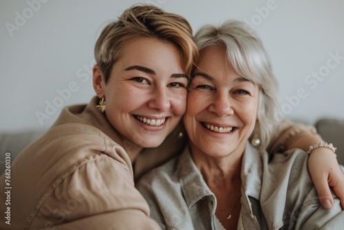 An intimate and cheerful portrait of a mother and daughter sharing a loving hug and genuine smiles.