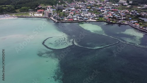 Drone footage of Wondam in Geumneung Beach, Jeju Island with buildings in the background photo