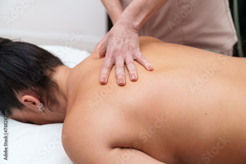 A therapist's hands press gently on a client's back in a soothing massage session.