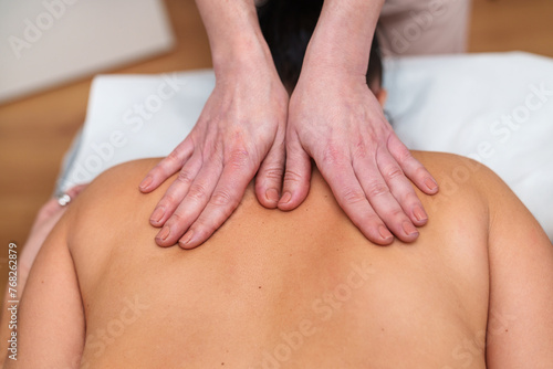 Focused hands massage a patient's back, promoting relaxation and wellness. © Koldo_Studio