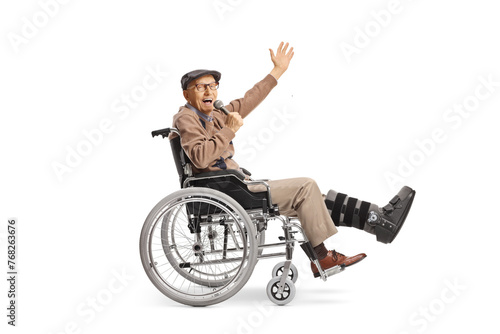 Cheerful elderly man with a broken leg in a wheelchair holding a microphone and singing