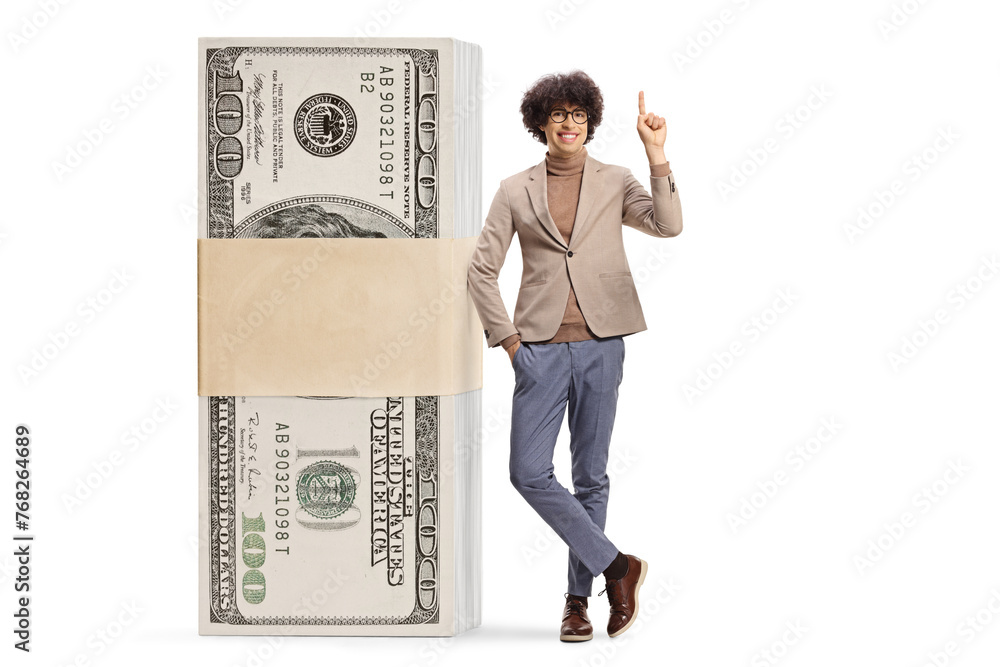 Young man next to a stack of money standing and pointing up Young man next to a stack of money standing and pointing up