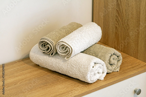 Clean folded towels on a shelf inside hotel room interior © Tatty