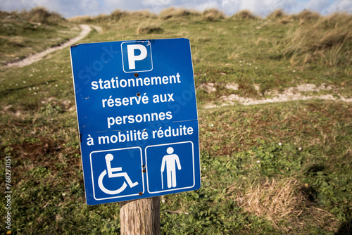 Photographie de signalétique de parking pour personnes à mobilité réduite telles que des personnes en fauteuils roulants ou personnes marchant avec une canne.