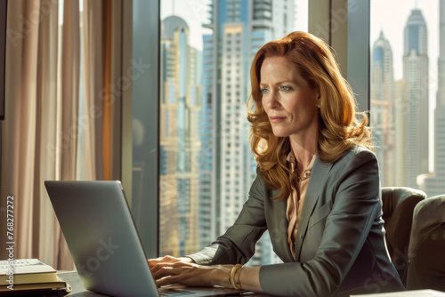 Businesswoman working on laptop in office with cityscape in background.
