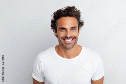 Portrait of handsome young man smiling and looking at camera while standing against grey background