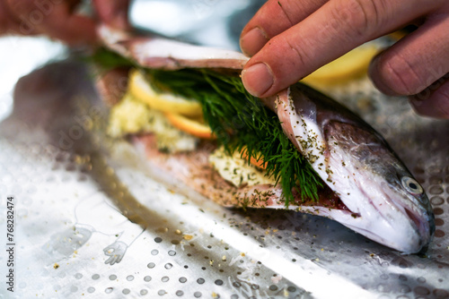 Preparing trouts with lemons butter and green dill.