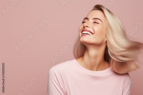 Happy young woman with long blonde hair on pink background. Cheerful female model.