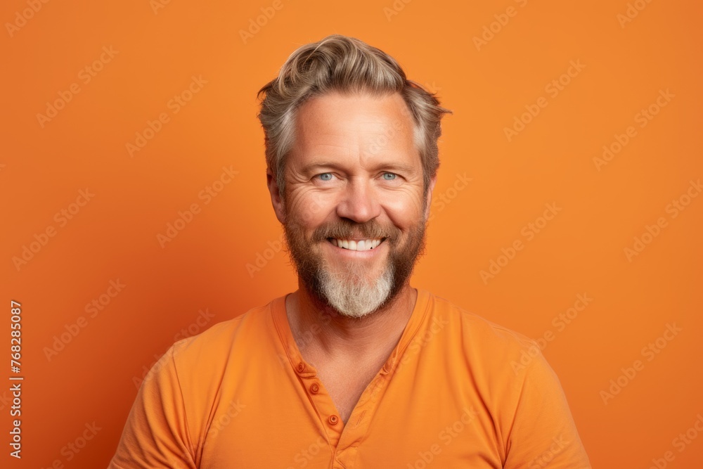 Portrait of a handsome mature man with beard and mustache on orange background Portrait of a handsome mature man with beard and mustache on orange background