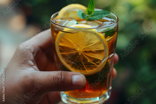 a hand holding a refreshing glass of iced tea, garnished with lemon slices and sprigs of mint, a cool and invigorating beverage enjoyed by city dwellers seeking respite from the summer heat