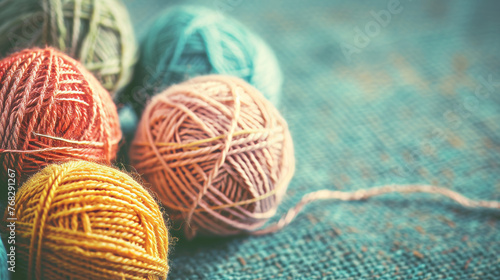 Balls of yarn in autumnal colors sit atop a textured surface, with a few loose threads suggesting ongoing craft work