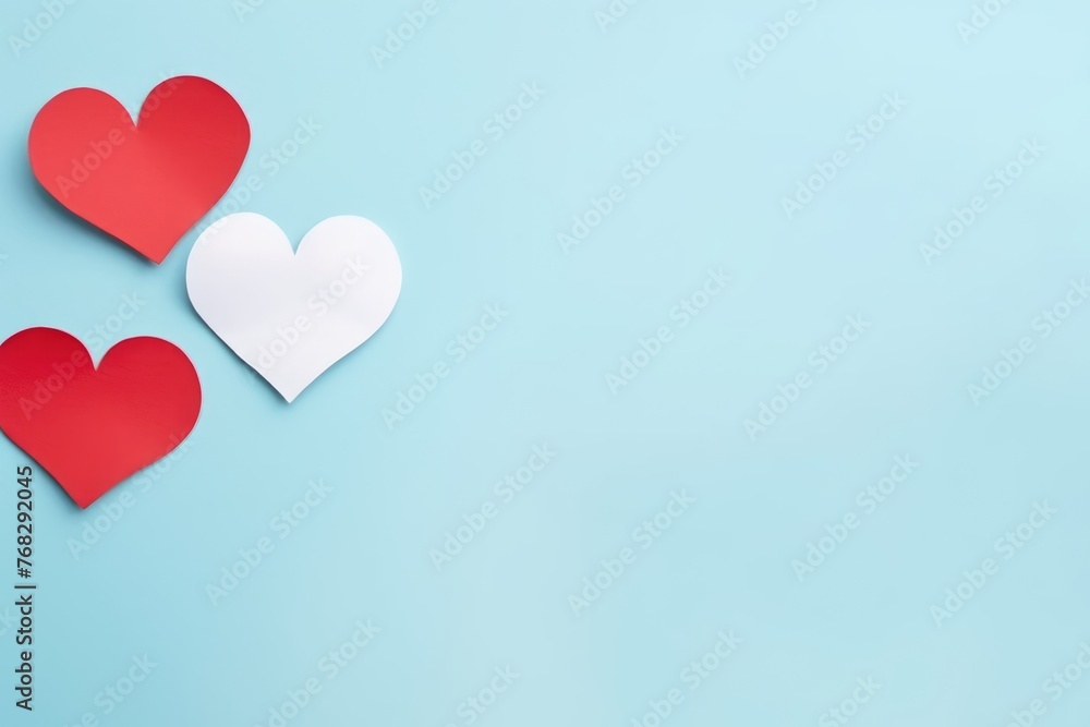 Red and white paper hearts forming a contrast against a soft blue background for a romantic theme.