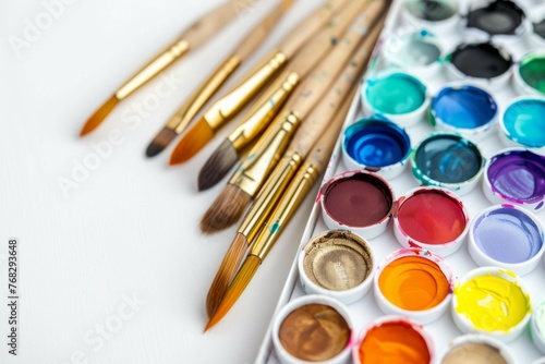 A beautifully arranged selection of vibrant watercolor paints alongside elegant bamboo brushes on a clean, white backdrop