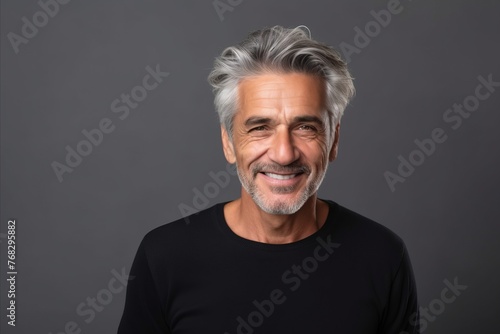 Portrait of a happy senior man smiling at the camera against grey background