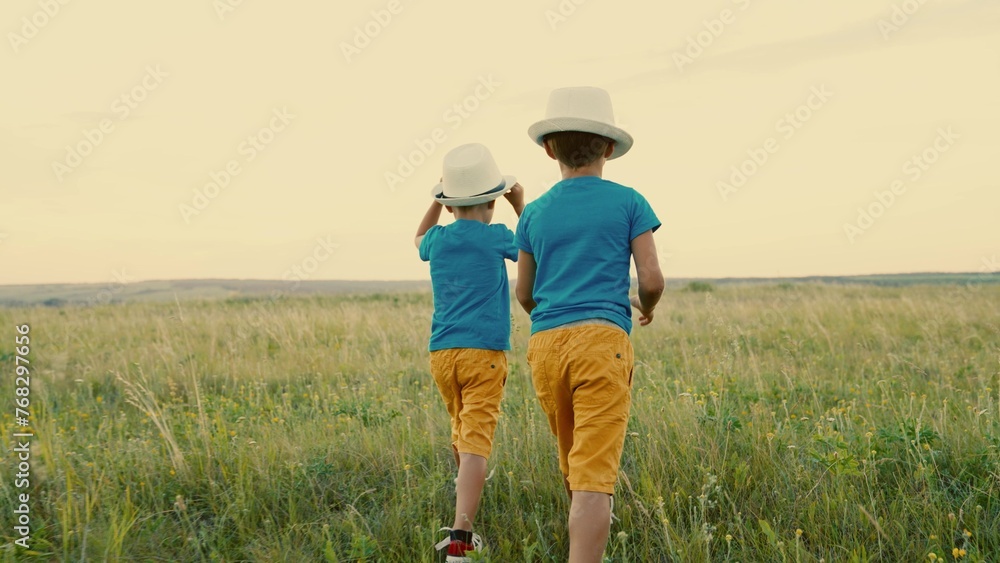 Boys play together in the park in spring at sunset. Children, friends, travel on a summer field. Children's dreams and fantasies in nature. Carefree children play together outdoors. A happy family