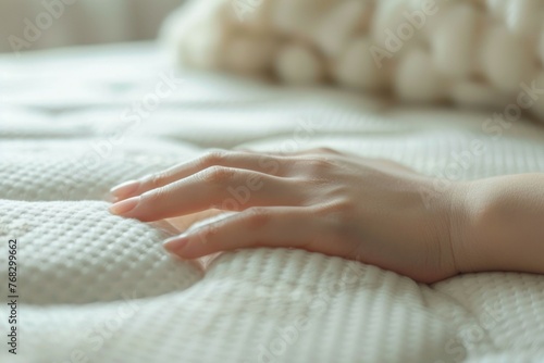 A hand is laying on a white mattress