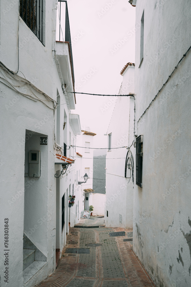 A narrow alley in a Spanish village with white walls and cobblestone street, embodying the quiet charm of rural Spain