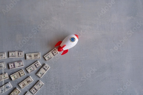 Foto Rocket blasts off through a pile of money