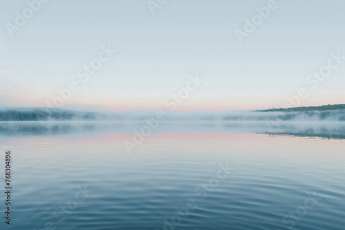 a serene lake at dawn  the surface like a mirror of silk reflecting the soft colors of the sky 