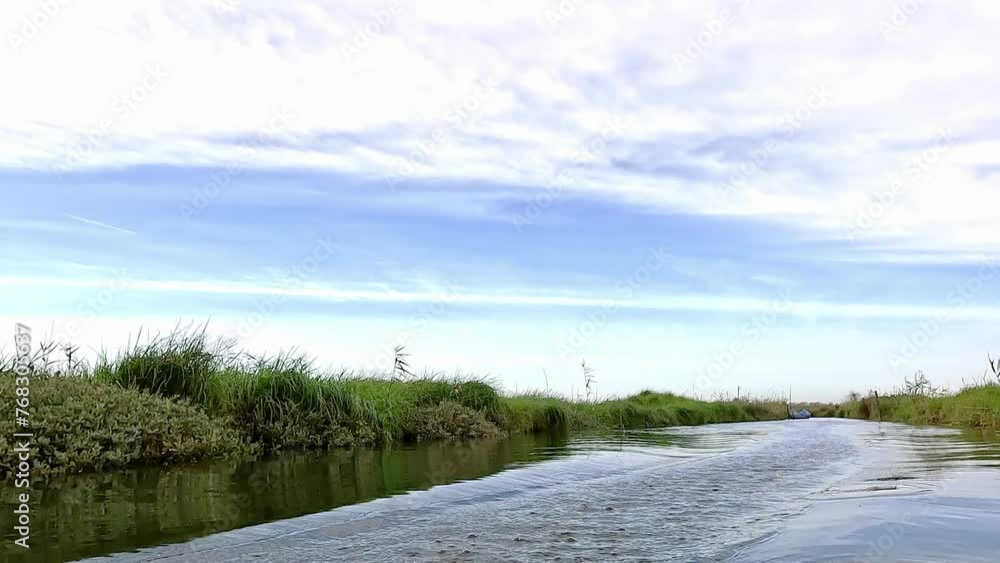 Hydrofoil rider gliding over the water with his board in one of the canals of the Ria de Aveiro in Portugal on a cloudy day. Hydrofoil rider gliding over the water with his board in one of the canals of the Ria de Aveiro in Portugal on a cloudy day.