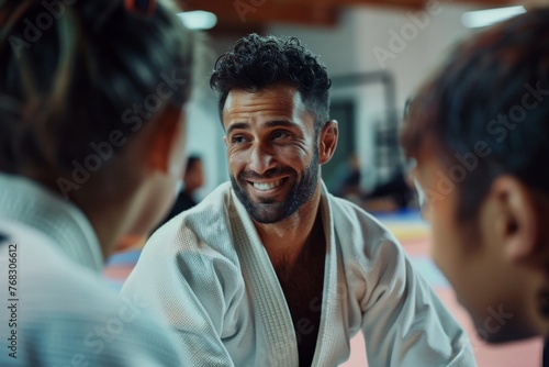 A smiling man interacts with others during a martial arts training session in a dojo