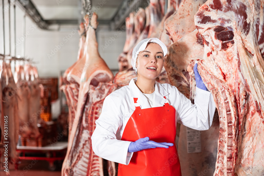 Female butcher showing beef chunk in meat storage
