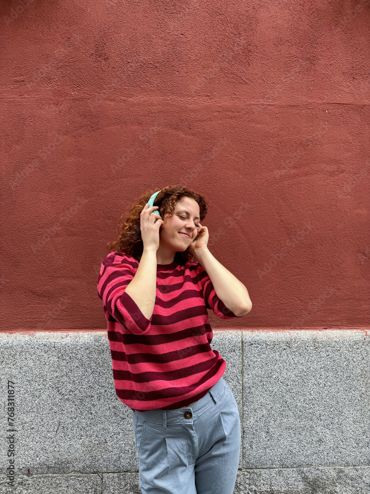 Young redhead woman enjoying music with headphones outside Young redhead woman enjoying music with headphones outside