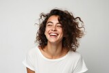 Portrait of a beautiful young woman with curly hair laughing on grey background