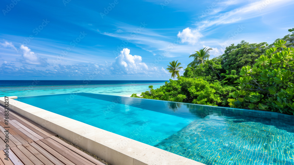 Infinity pool with blue water on the sandy beach with view to crystal clear turquoise ocean