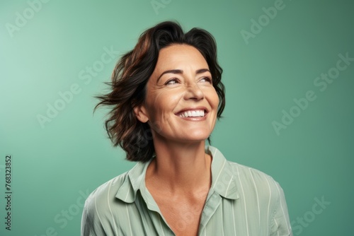 Portrait of smiling middle aged businesswoman looking up over green background