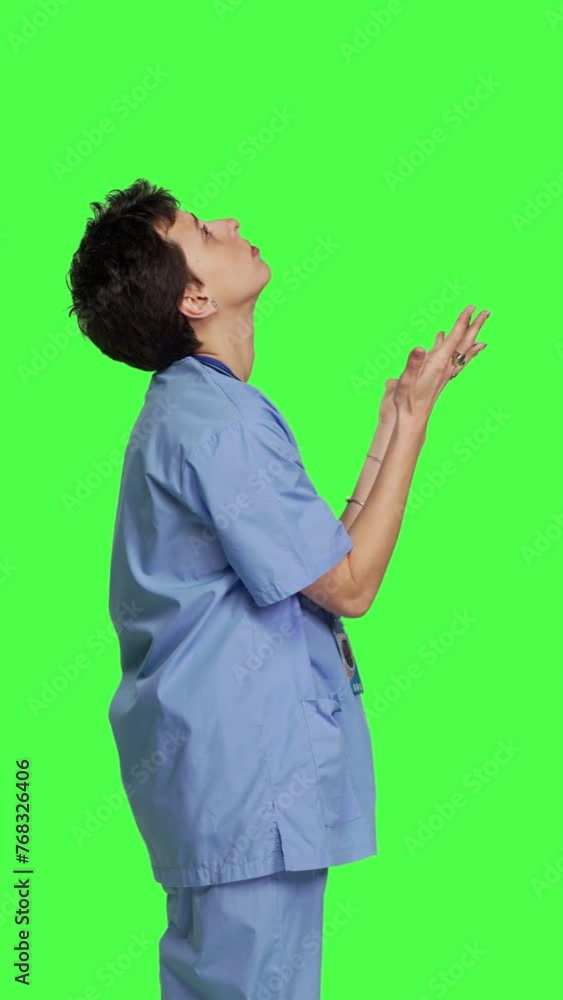 Profile Hospital nurse worshipping God by prayer against greenscreen backdrop, praying to jesus christ and having hope in christianity and spirituality. Medical assistant doing meditation. Camera B.