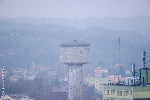 Stara charakterystyczna wieża ciśnień na terenie dawnej huty w Ostrowcu w mgliste marcowe popołudnie. Widok na miasto (jego historyczną część) w mglisty dzień o „świcie” wiosny.