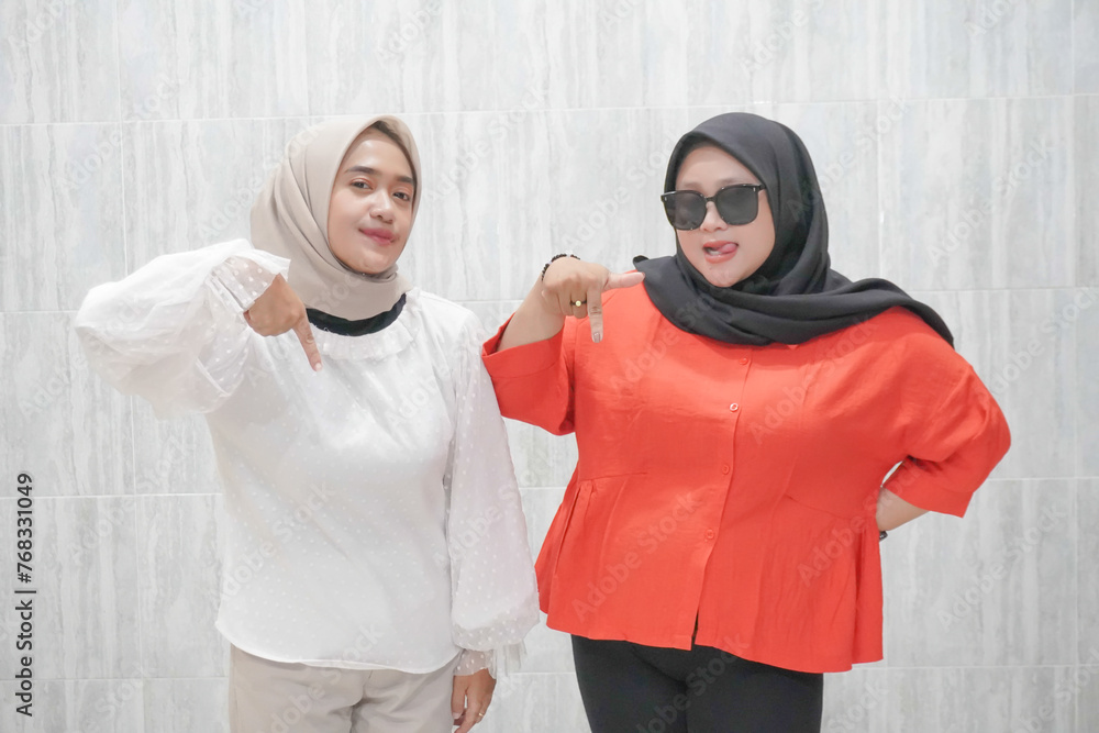 The happy expression of two women wearing hijabs in white and red clothes