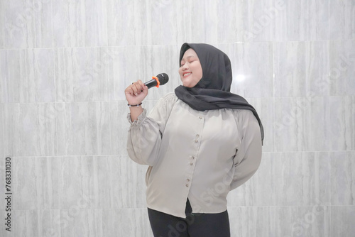 Expression of a smiling Asian Indonesian woman wearing a hijab wearing a white shirt